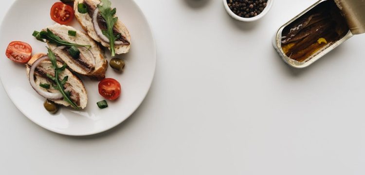 Top view of delicious Mediterranean dish with anchovies, olives, and tomatoes on white background.