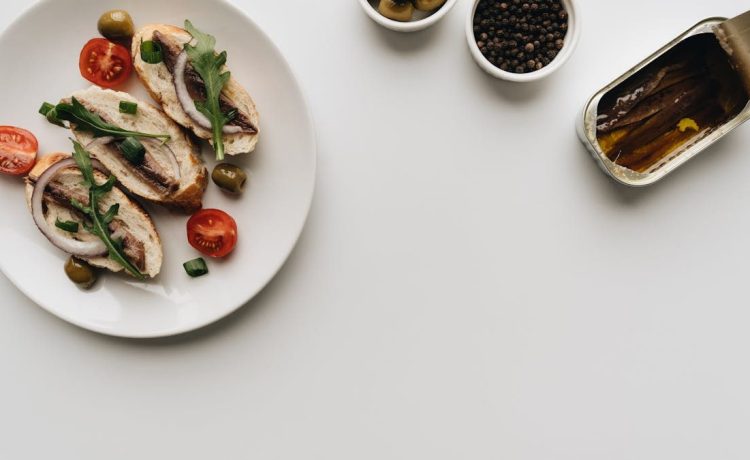 Top view of delicious Mediterranean dish with anchovies, olives, and tomatoes on white background.
